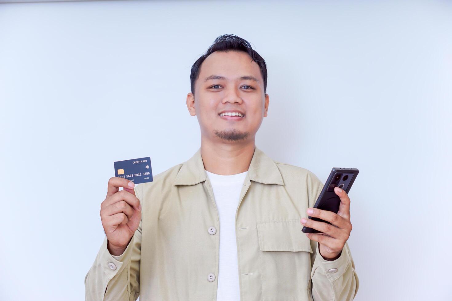 A cheerful man holding a smartphone and credit card, ready for a transaction. photo