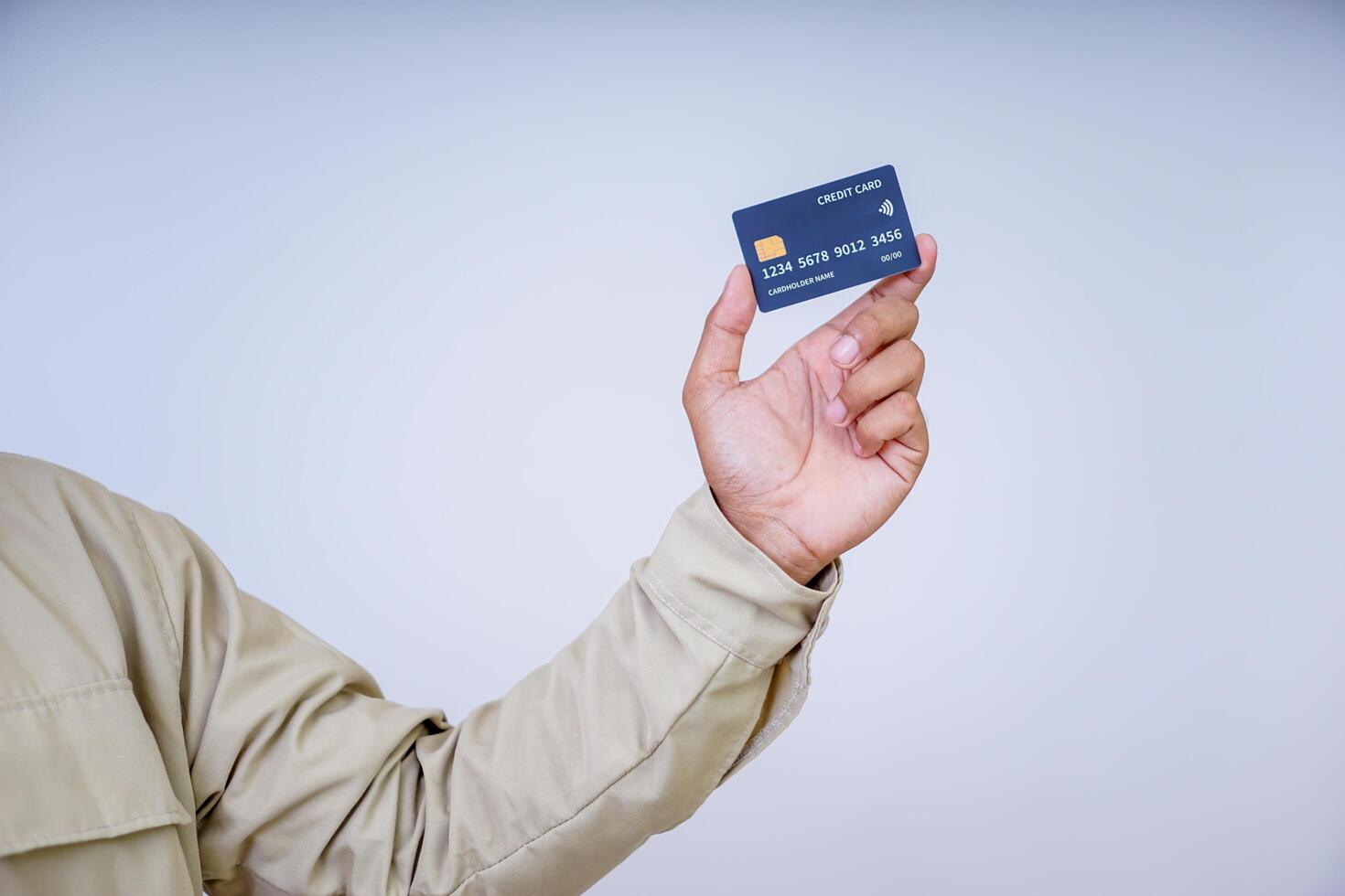 A hand holding a modern credit card with a microchip against a plain background. photo