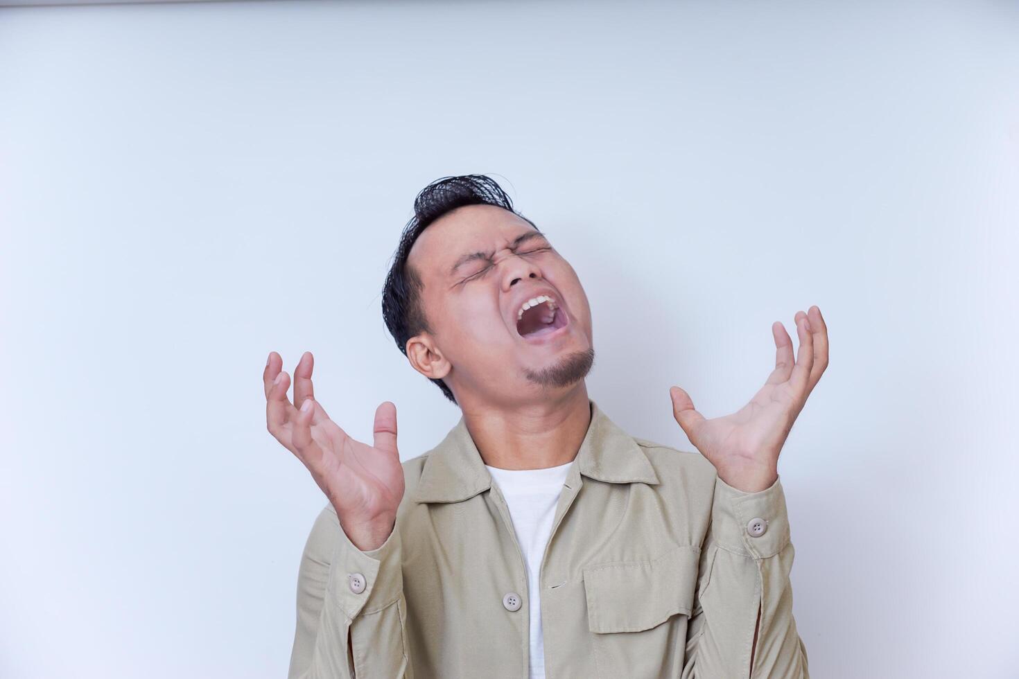 A man expresses frustration with his hands on his head and a shout. photo