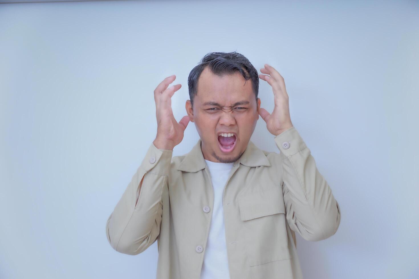 A man expresses frustration with his hands on his head and a shout. photo