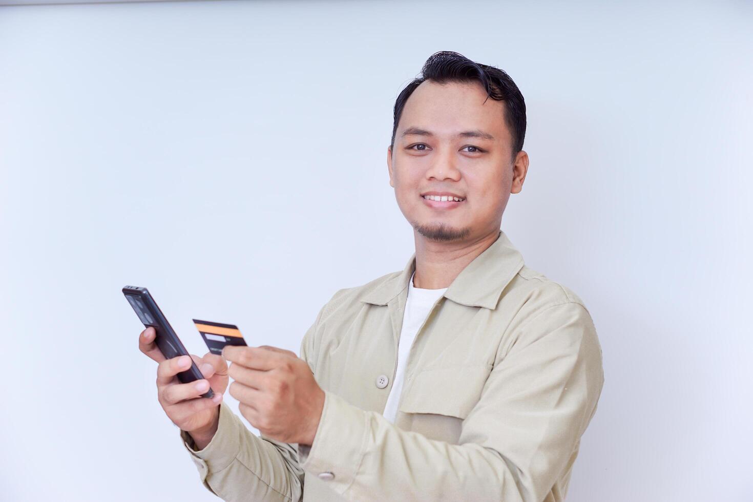 A cheerful man holding a smartphone and credit card, ready for a transaction. photo