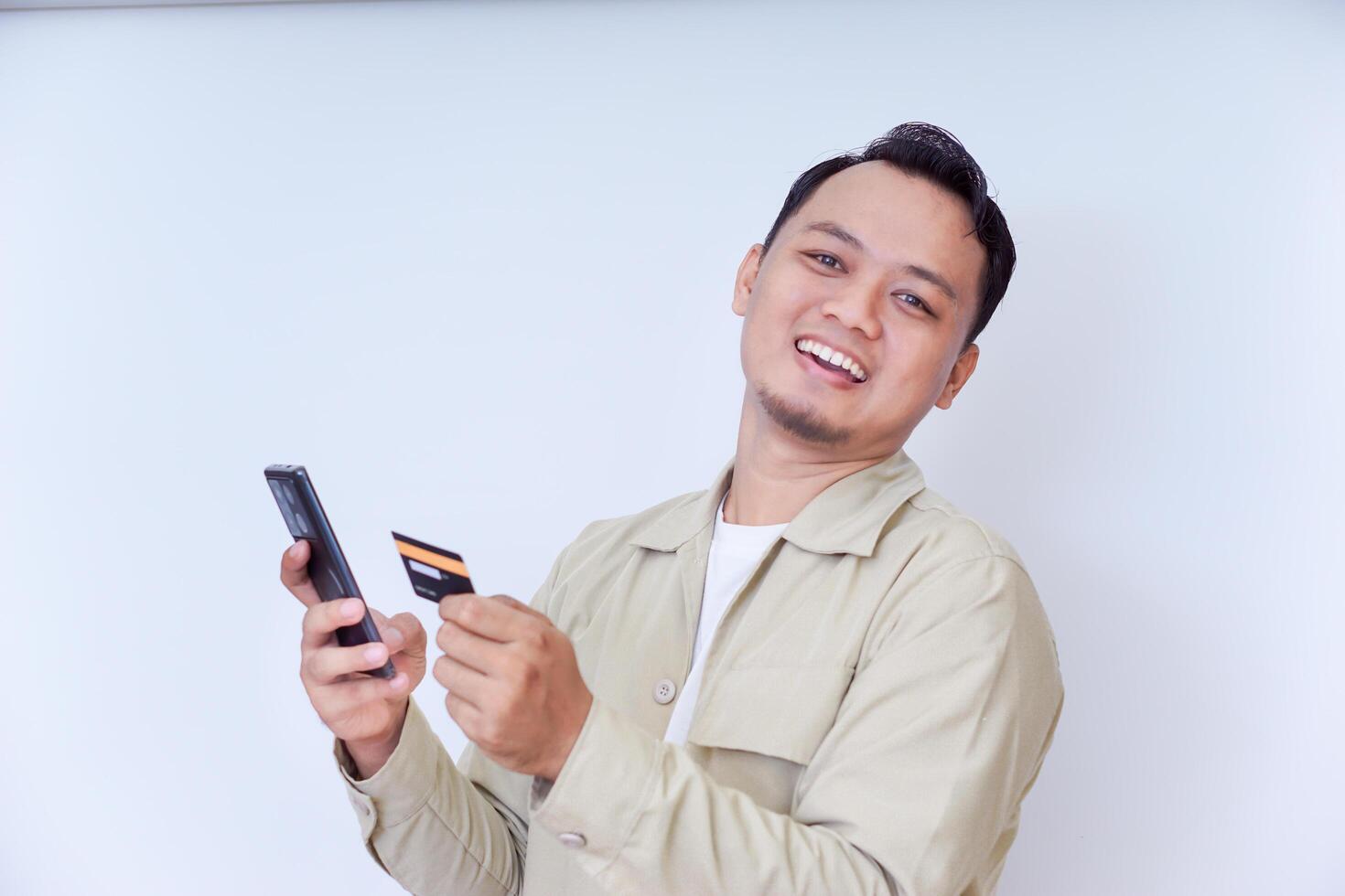 A cheerful man holding a smartphone and credit card, ready for a transaction. photo