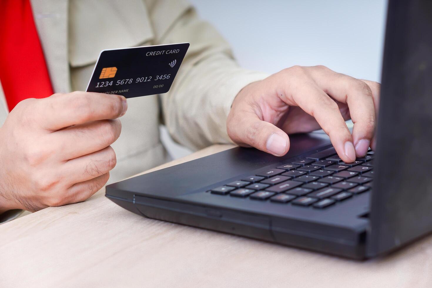 A person using a laptop while holding a credit card, illustrating online shopping. photo