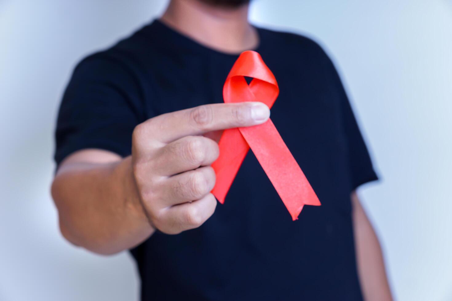 A person holding a red ribbon, symbolizing awareness and support for health issues. photo