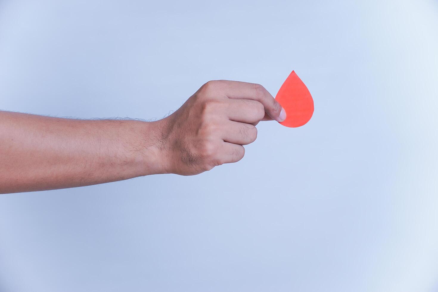 a hand hold a drop of donor blood with white background. world blood donor day concept, photo