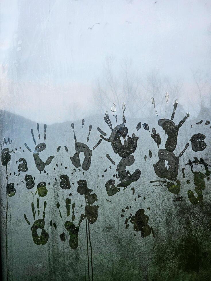 Handprints on a foggy window create a mysterious and artistic scene. photo