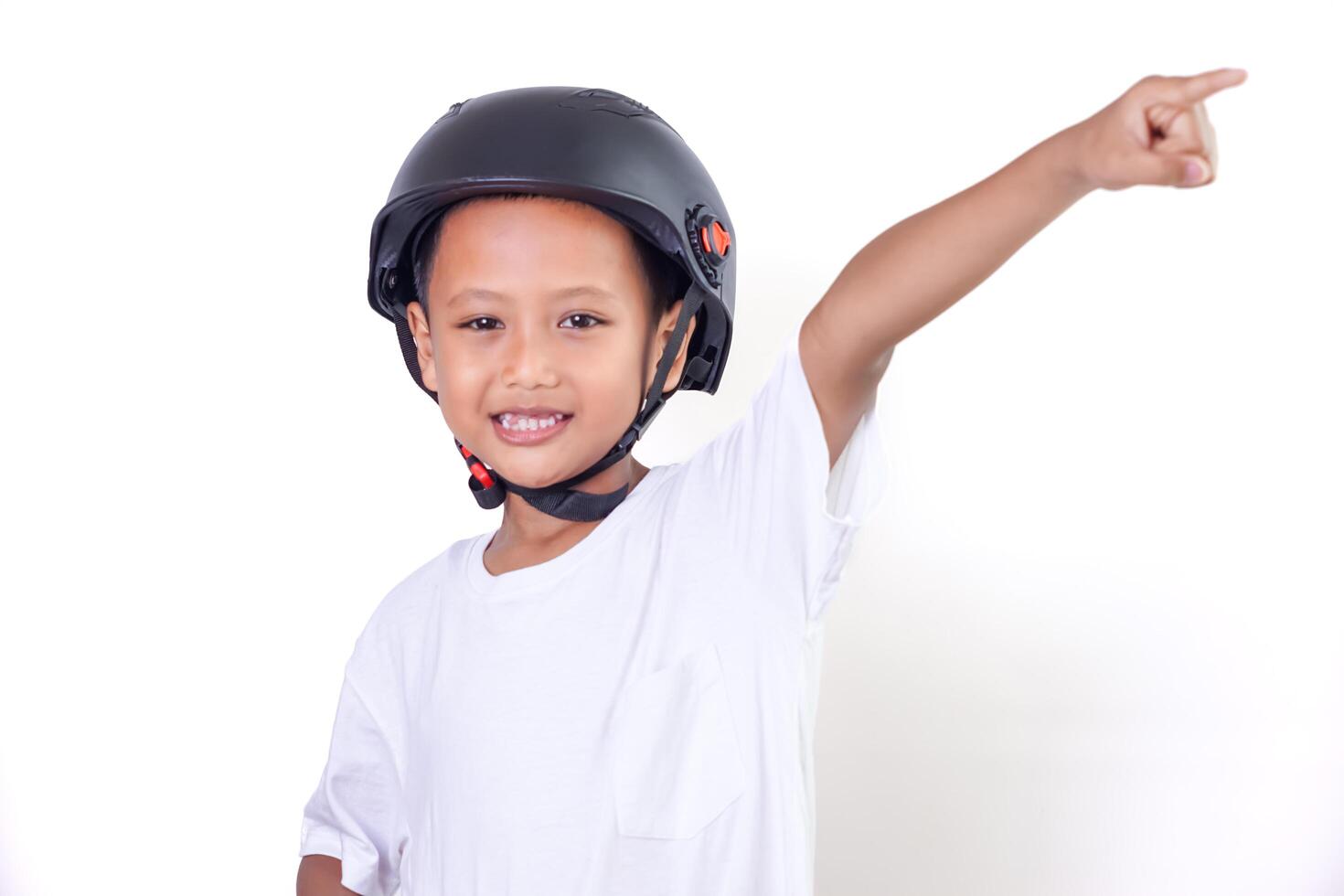 A cheerful asian boy in a helmet points upwards with a bright smile. photo