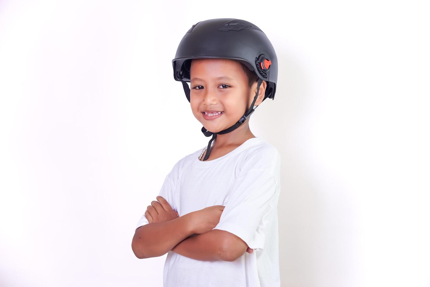 A young asian boy smiles confidently while wearing a helmet and a white shirt. photo