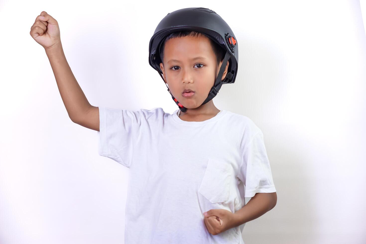 A cheerful asian child wearing a helmet, celebrating with raised fists and a bright smile. photo