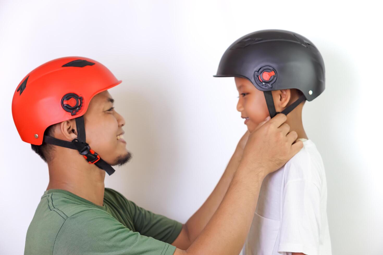 A asian father helps his son wear a helmet, ensuring safe and fun outdoor riding. photo