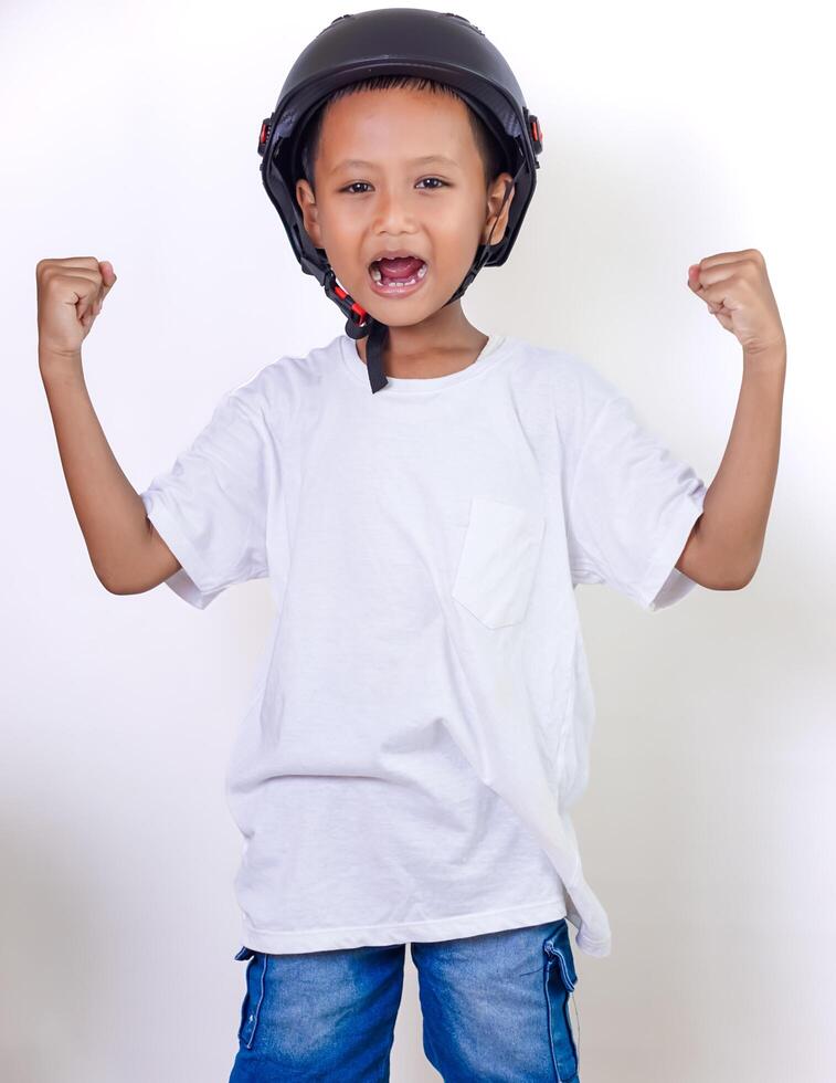 A cheerful asian child wearing a helmet, celebrating with raised fists and a bright smile. photo