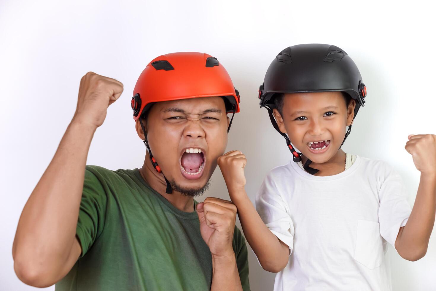A asian father and son celebrate together, wearing bright helmets and showing excitement. photo