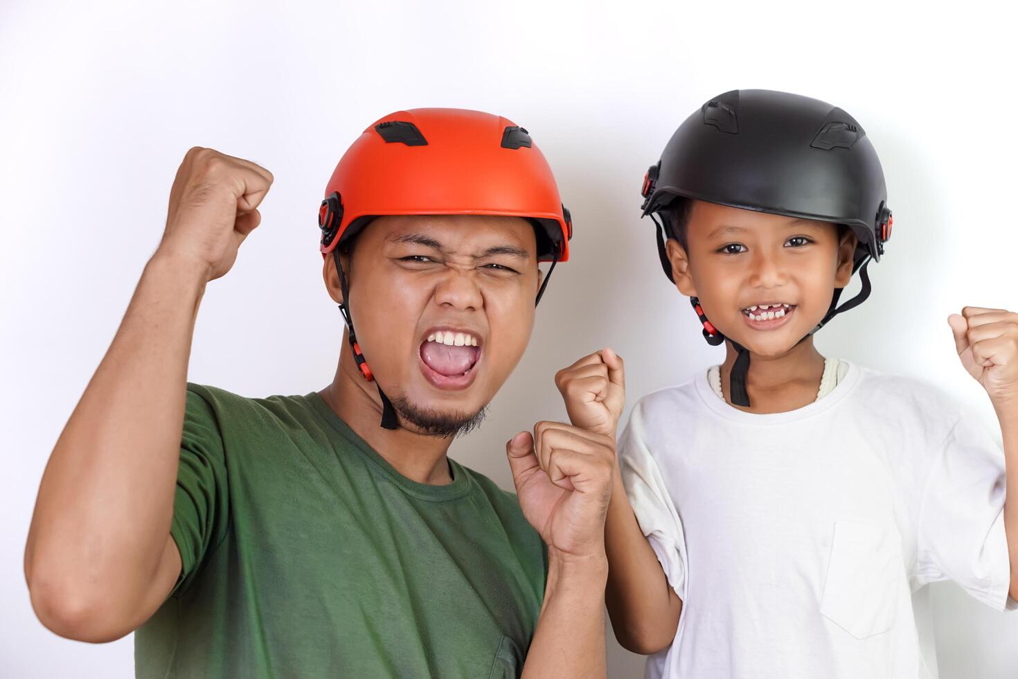 A asian father and son celebrate together, wearing bright helmets and showing excitement. photo