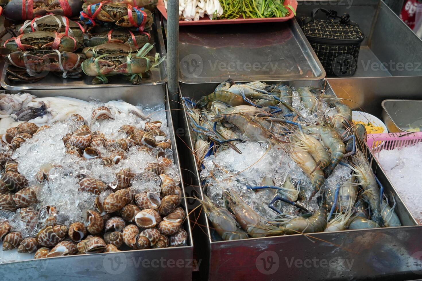 fresh seafood display at night street food vendor stall, there is shrimps, clamps, and crabs on ice photo