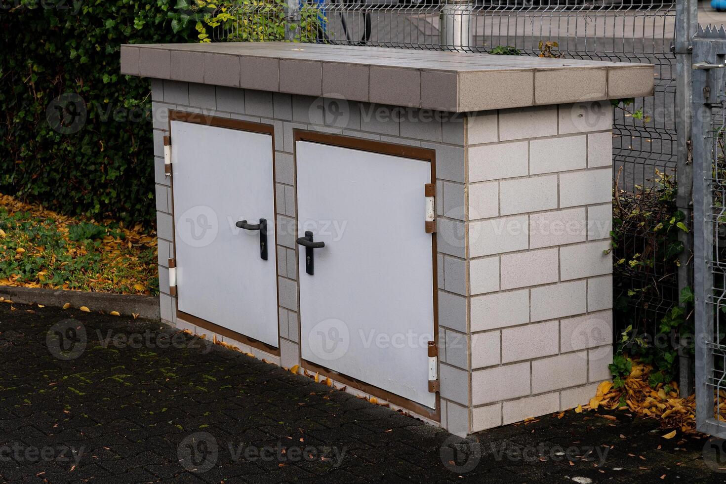 A concrete utility storage unit with two white doors is placed in a photo