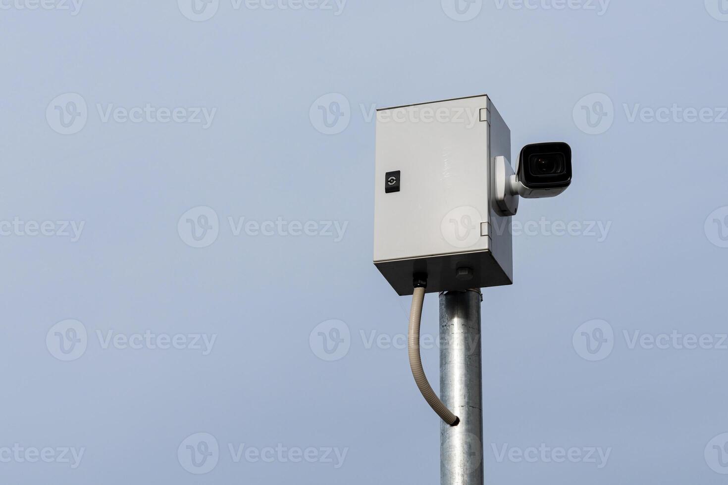 Security camera mounted on a metal pole against a clear sky photo