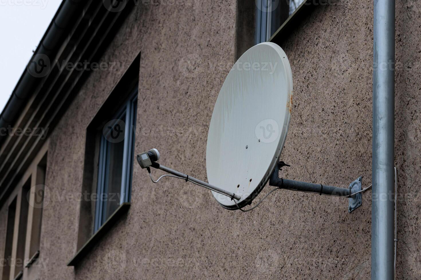 Satellite dish mounted on residential building exterior in urban area photo