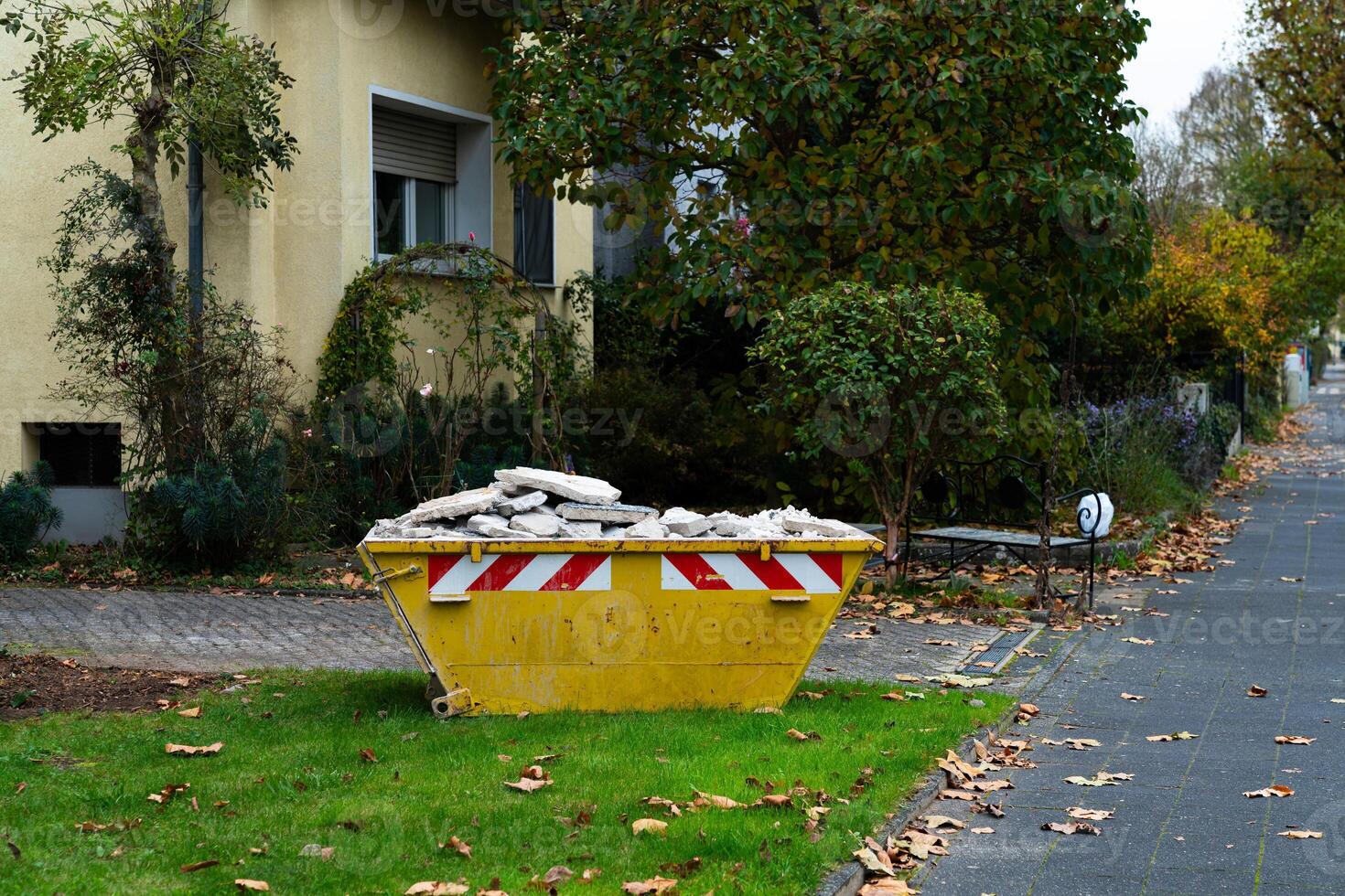 A bright yellow debris bin filled with construction waste sits on a photo