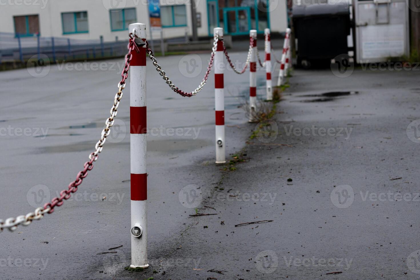 Chain-linked posts line a wet surface in an empty parking area photo