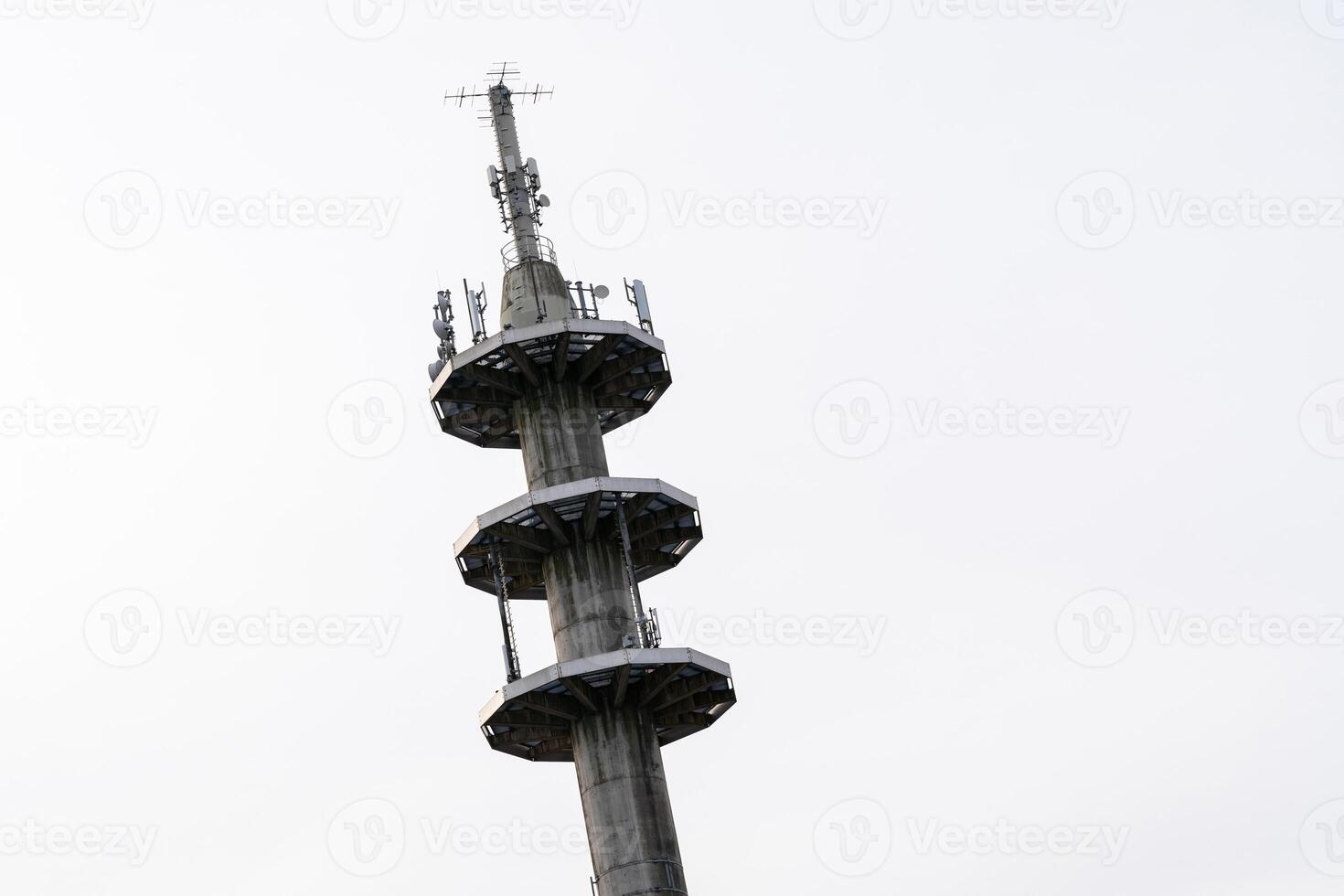 A tall communication tower stands prominently in an urban landscape photo