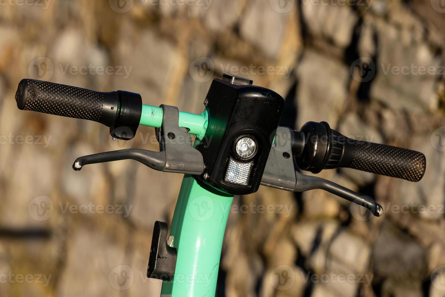 Green e-scooter handlebars against a textured background photo