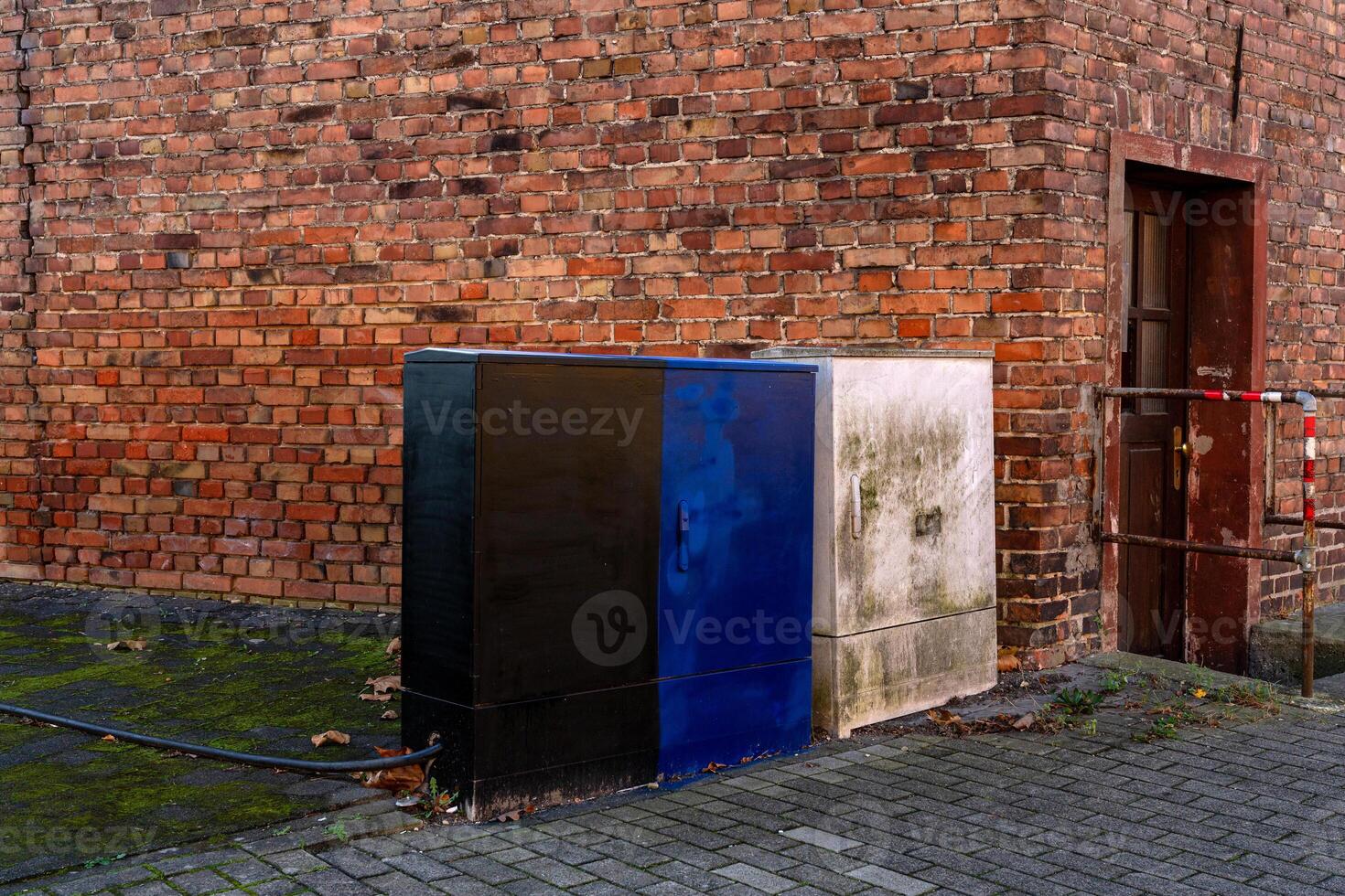Colorful utility boxes against a brick wall in an urban setting photo