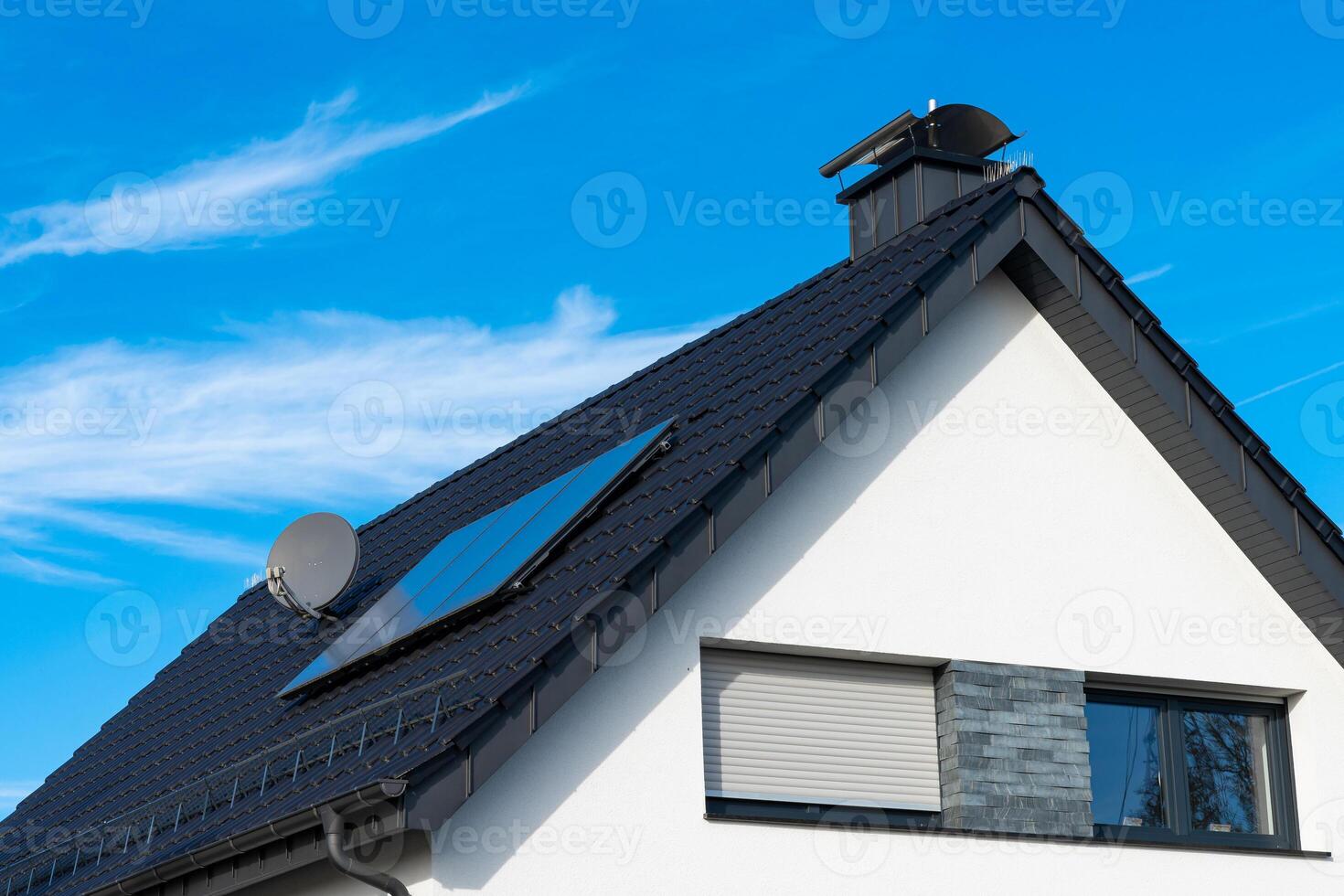 Modern house with solar panels and satellite dish on clear day photo