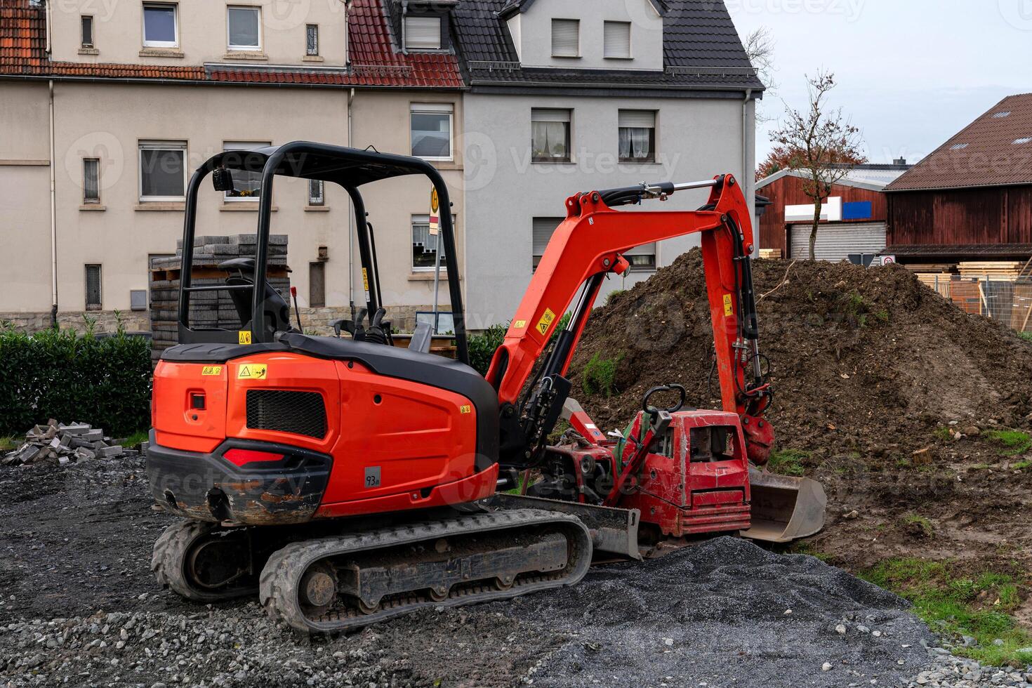 A red excavator and small digging machine work on a construction site photo