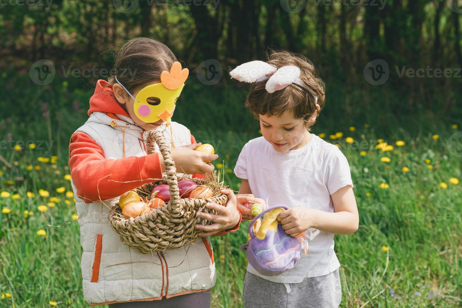 Two children hunt for Easter eggs in a spring garden. Easter tradition photo