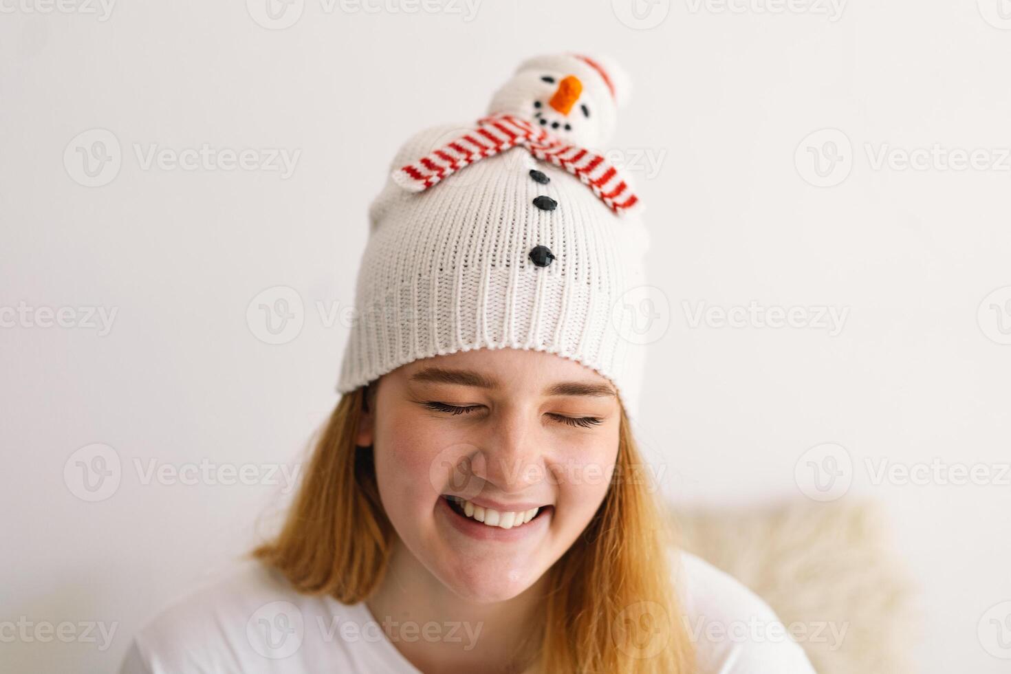 Funny young girl in a Christmas hat with a snowman and a red scarf. photo