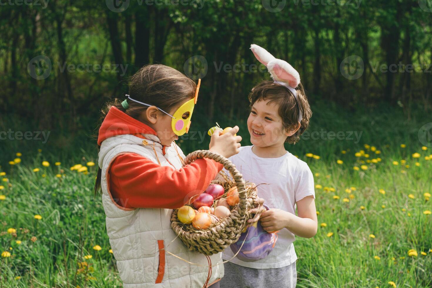 Two children hunt for Easter eggs in a spring garden. Easter tradition photo