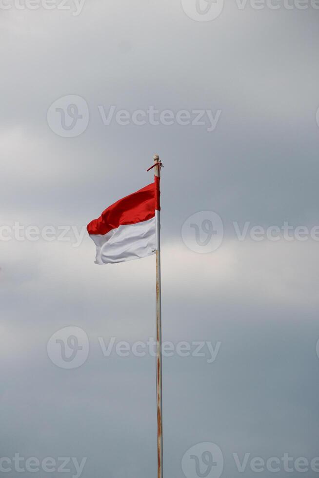 Indonesian flag fluttering in the wind with dark clouds in the background. photo
