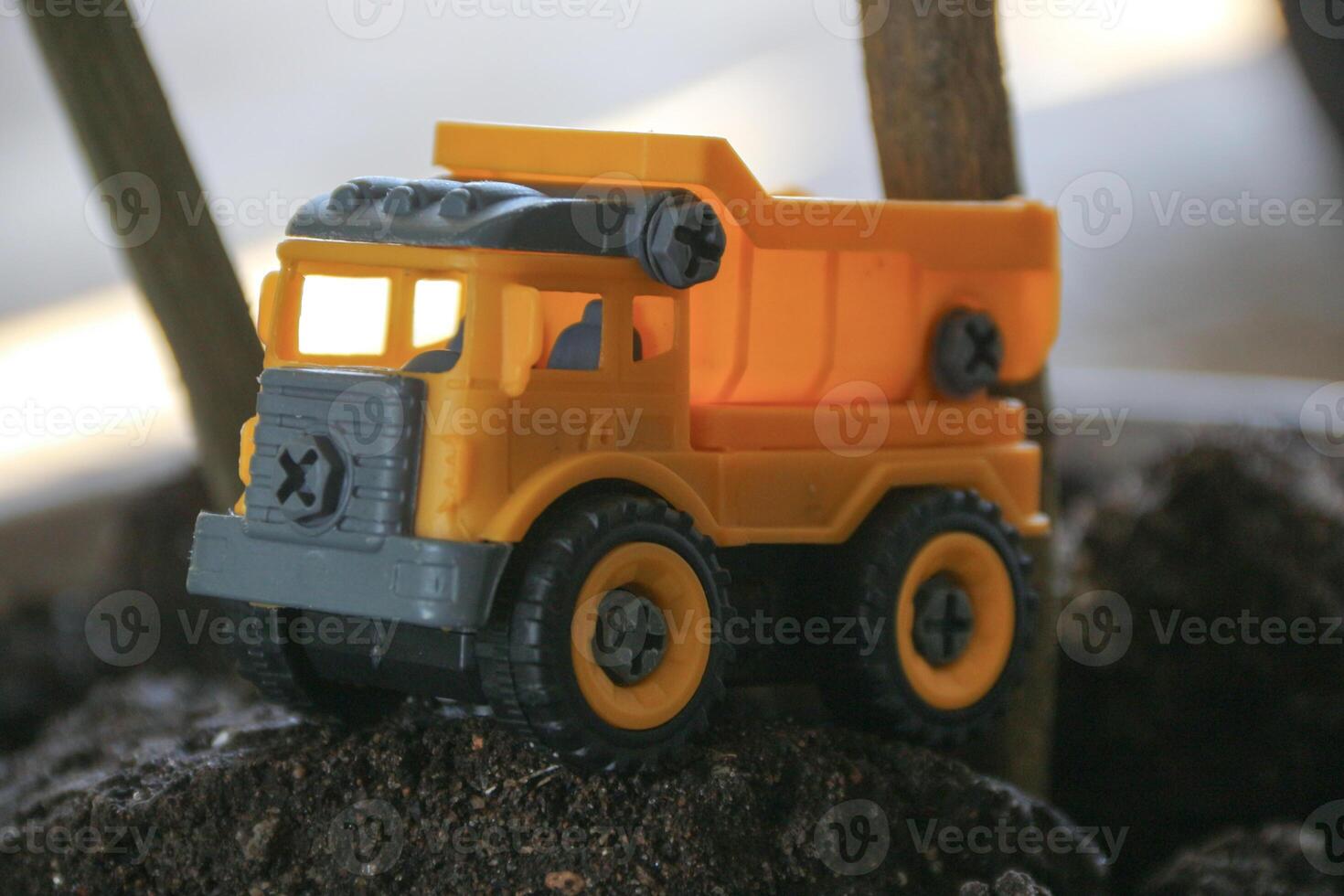 Children's toy colored small truck on the grass background of sand and stones loaded with cargo photo