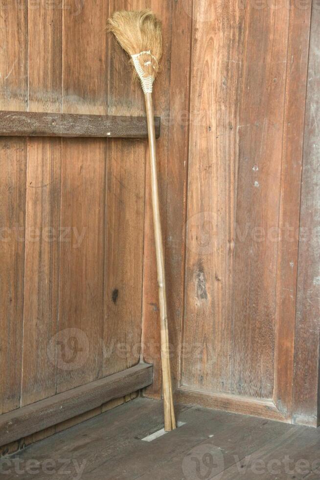 Display of traditional long-handled broom made of coconut fiber and a kind of plant photo