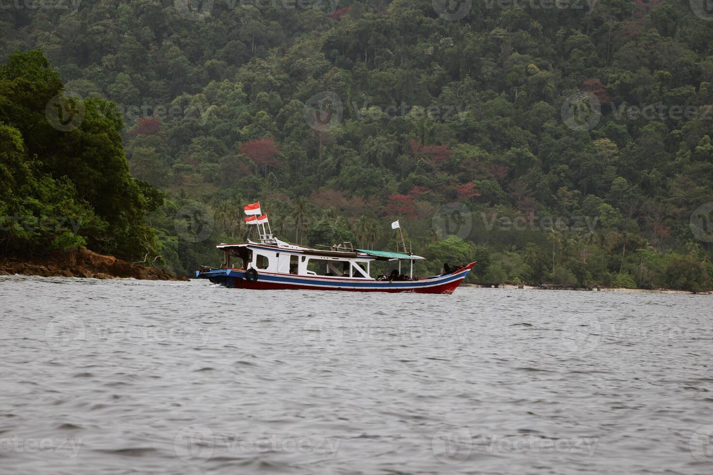 Traditional blue wooden boat heading to the resort in Pahawang during summer holidays photo