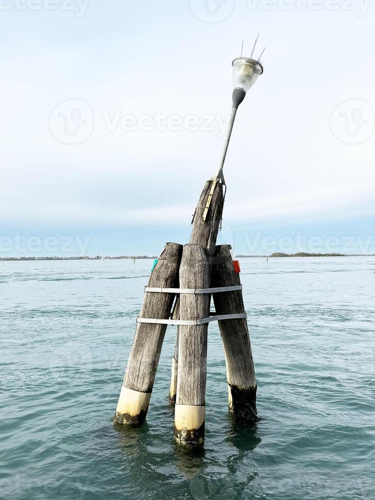 Wooden navigation buoy in calm ocean waters under clear sky photo
