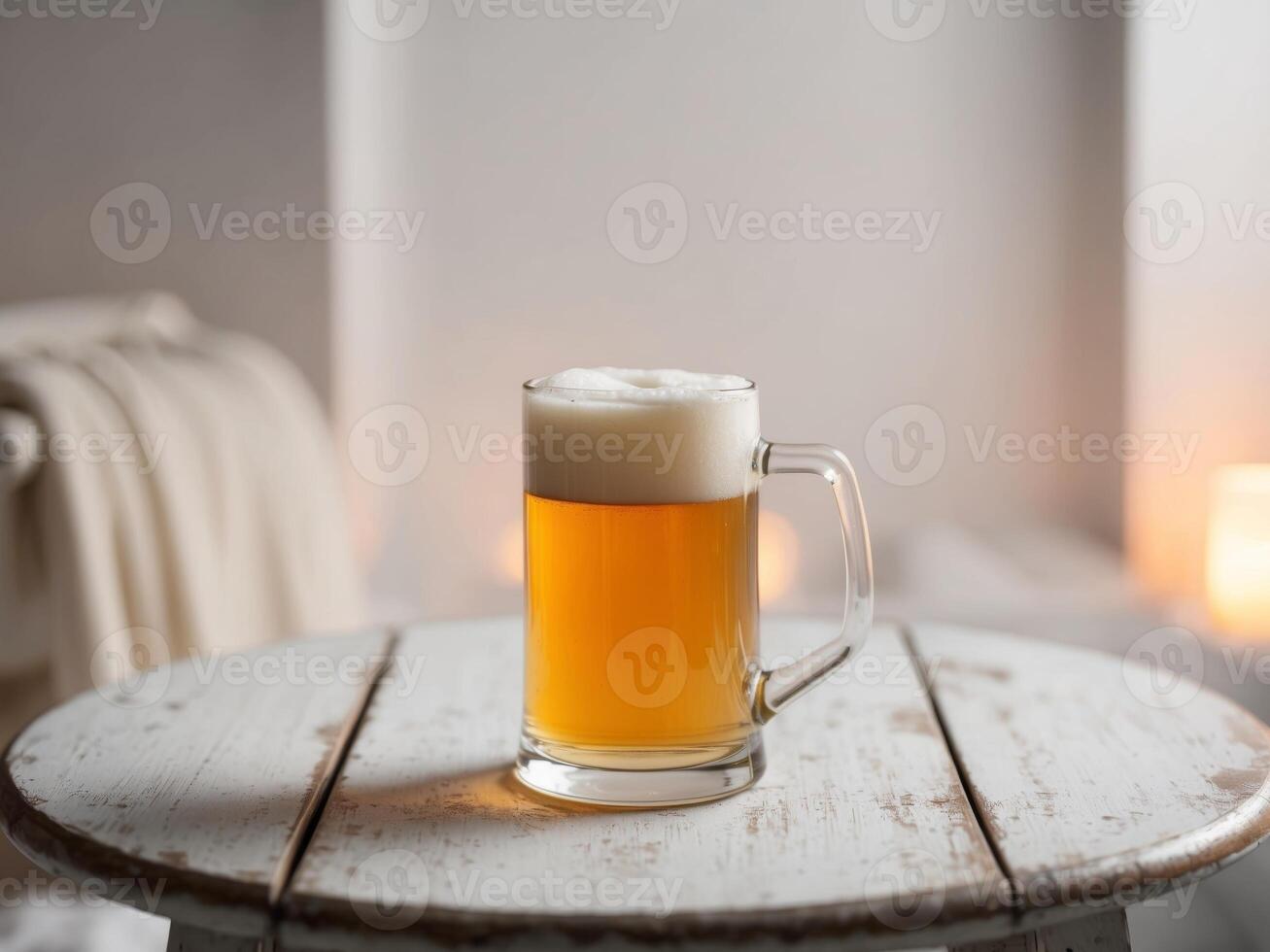 A glass of beer on a table in front of a candle photo