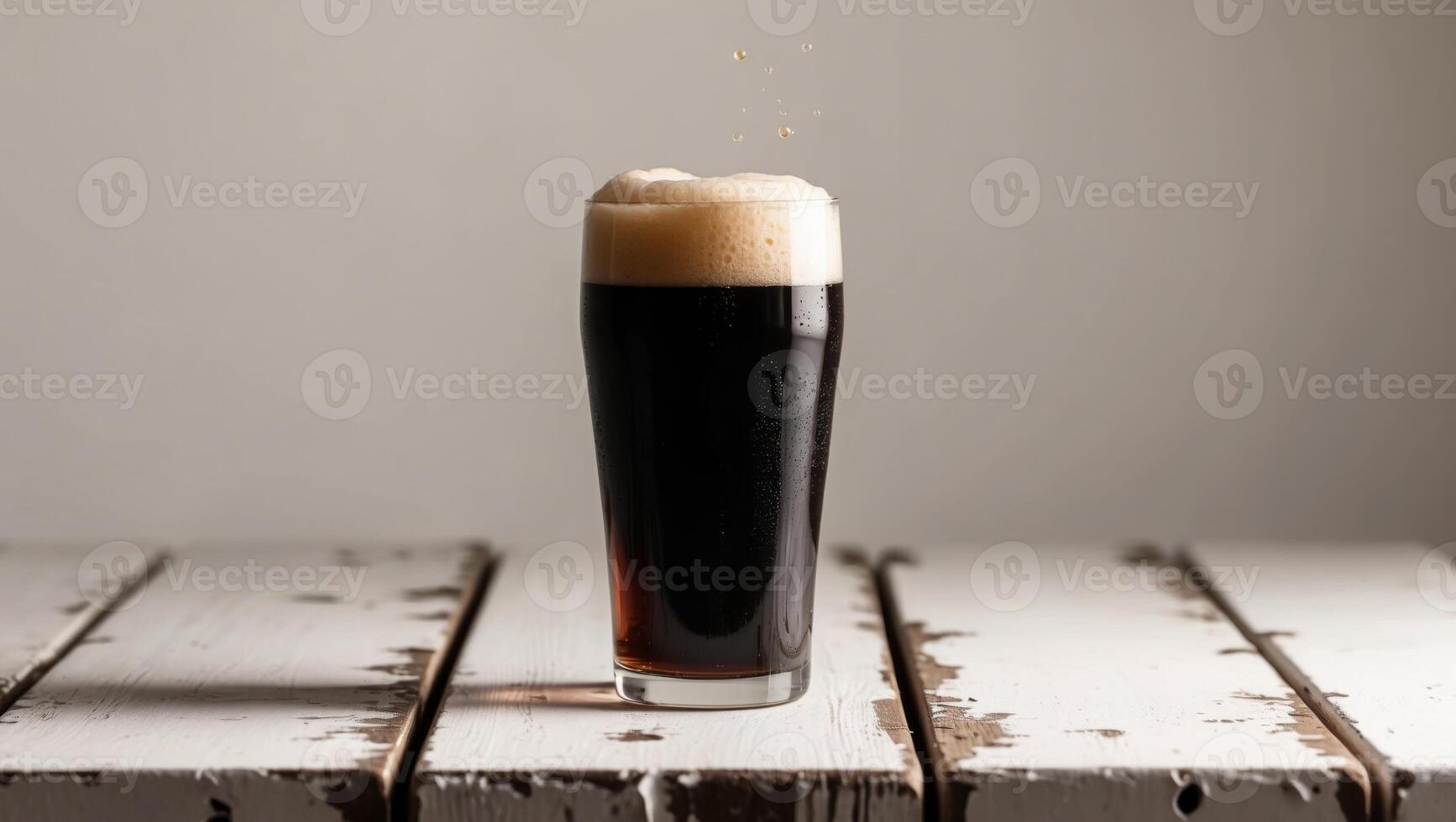 A dark beer is sitting on top of a wooden table photo