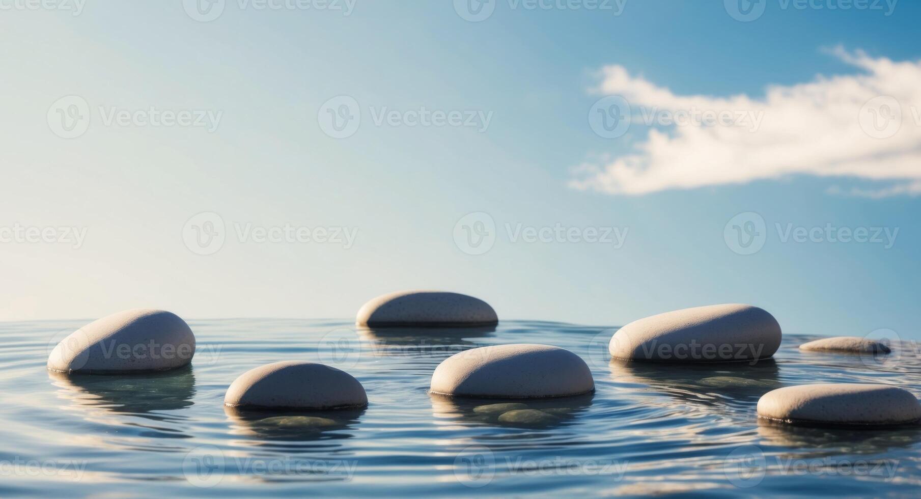A group of stones in the water with a blue sky photo