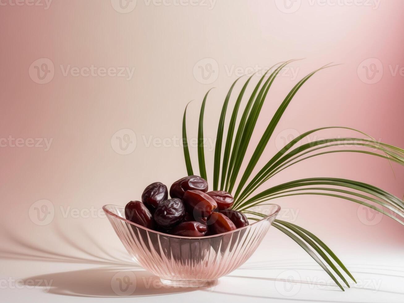 Dates in a glass bowl on a pink background photo