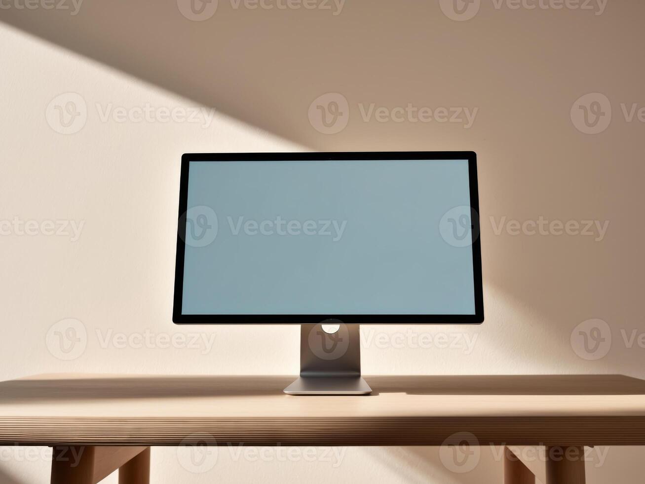 A computer monitor on a wooden table in front of a wall photo