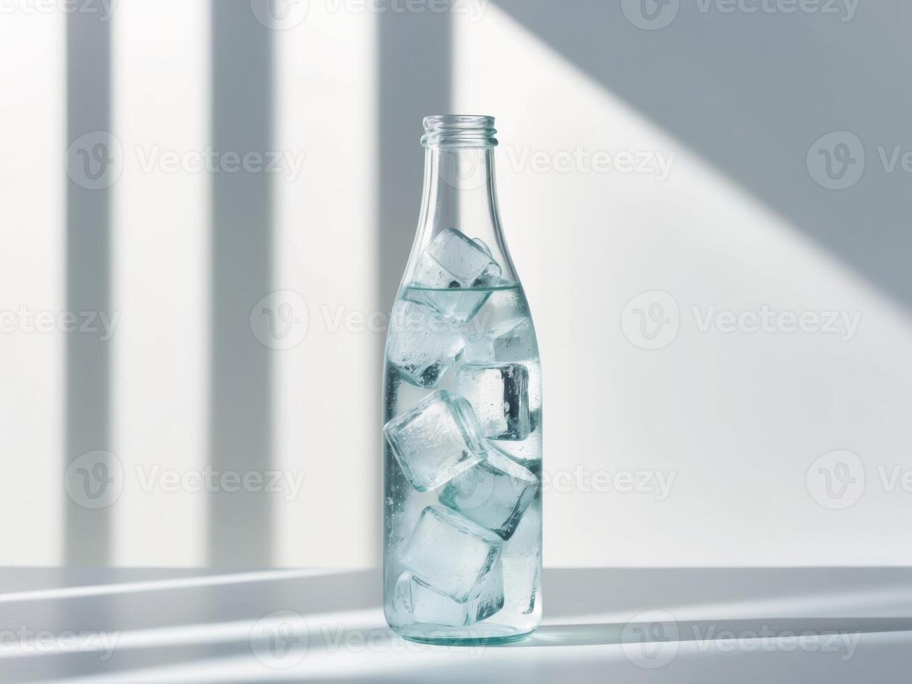 A bottle of water with ice cubes on a table photo