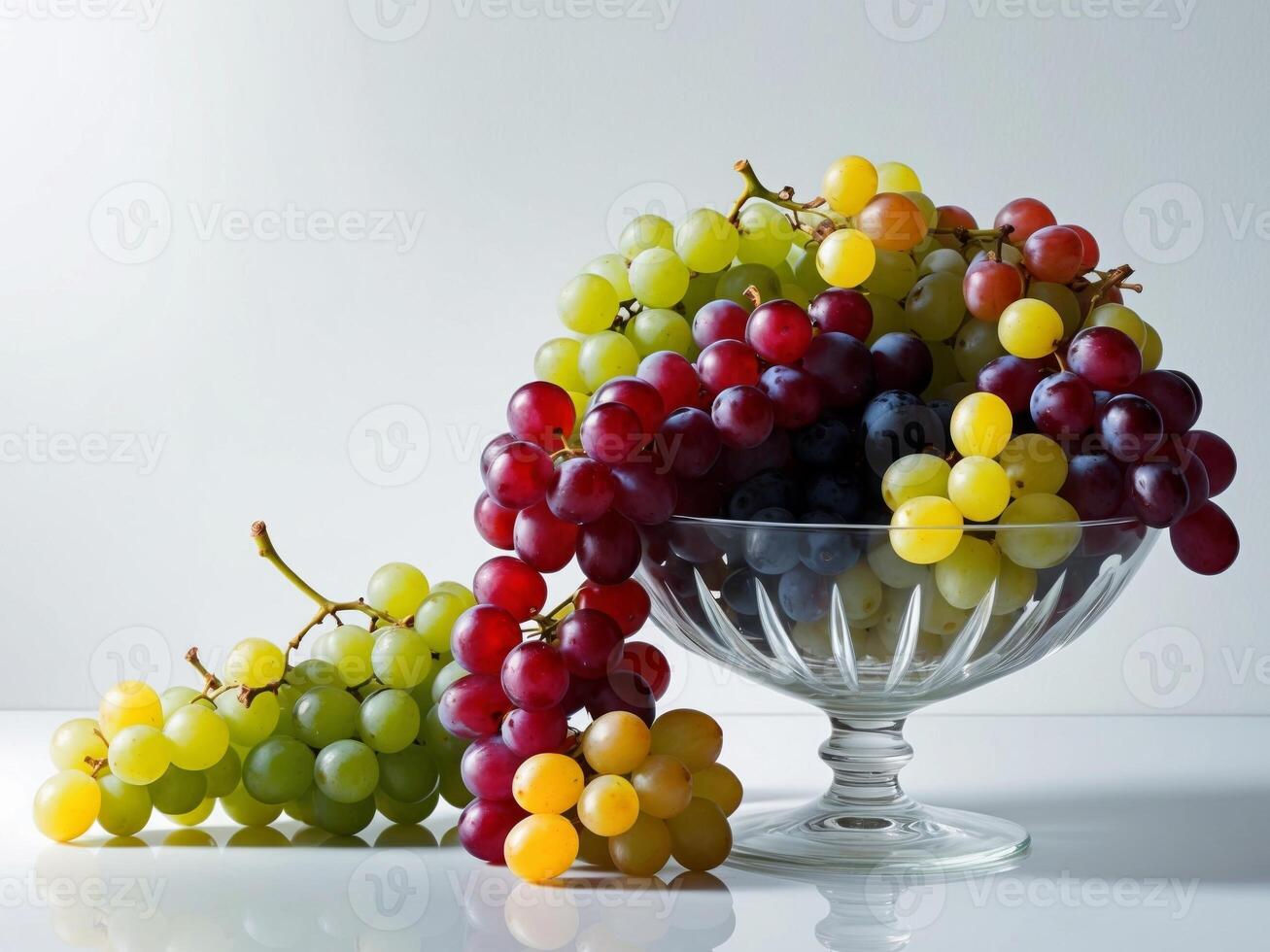 A glass bowl filled with grapes on a white surface photo