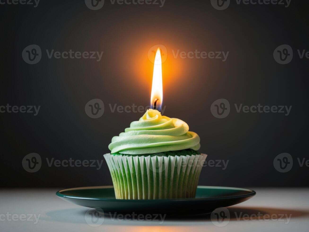 A cupcake with a green frosting and a lit candle photo