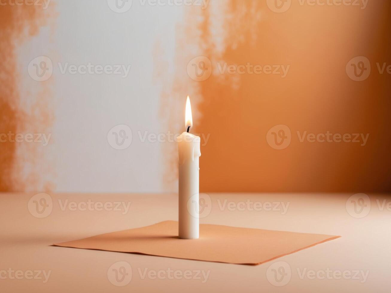 A single candle on a piece of paper on a table photo