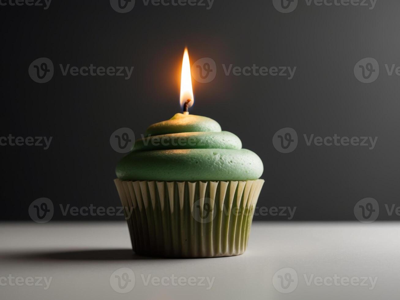 A green cupcake with a single candle on top photo
