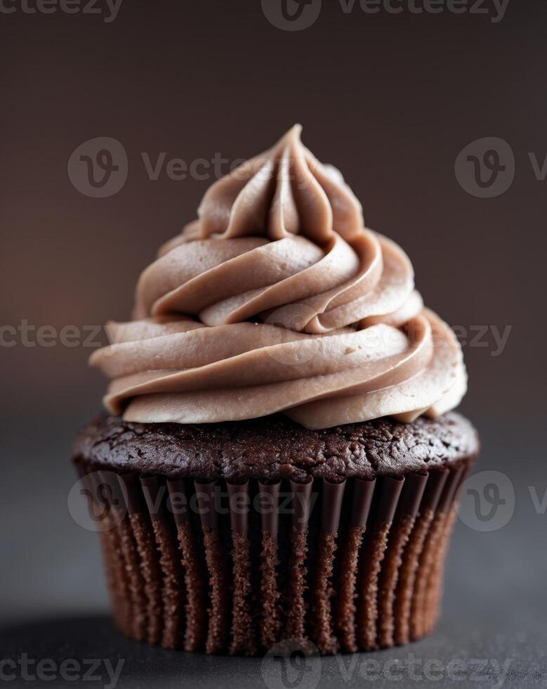 Close up of a chocolate cupcake with creamy frosting decorated in soft swirls on a dark background photo