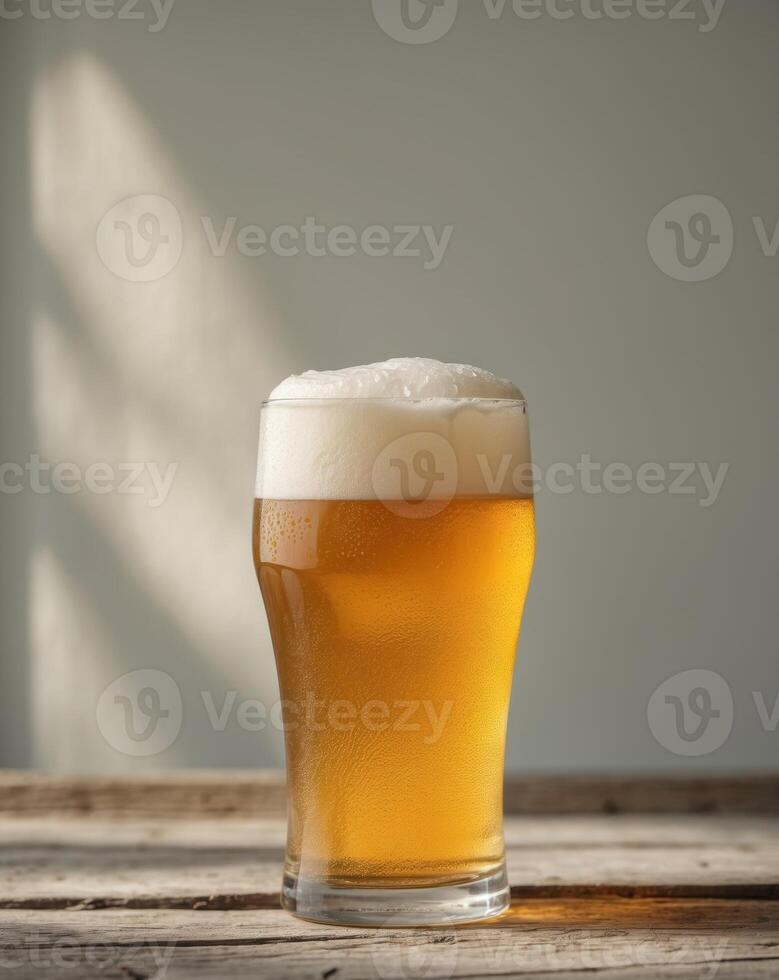 Clear Glass Pint of Golden Beer with Foamy Head on Wooden Table photo