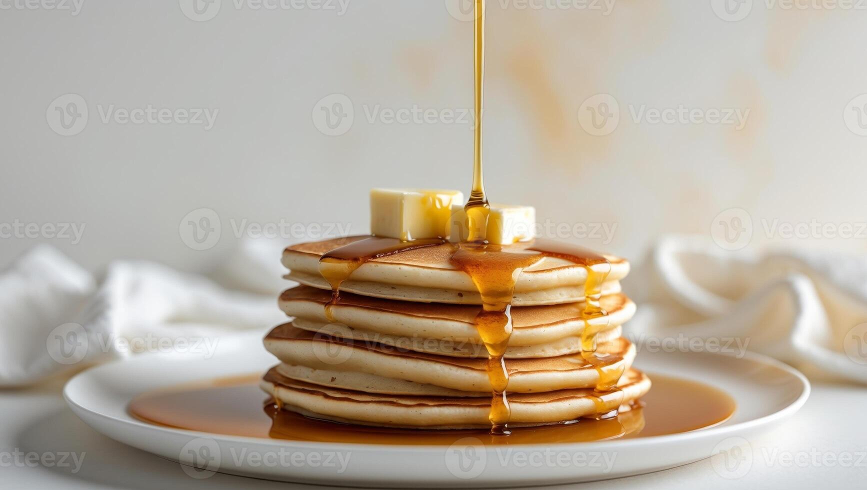 Stack of fluffy pancakes drizzled with syrup and melting butter on a white plate photo