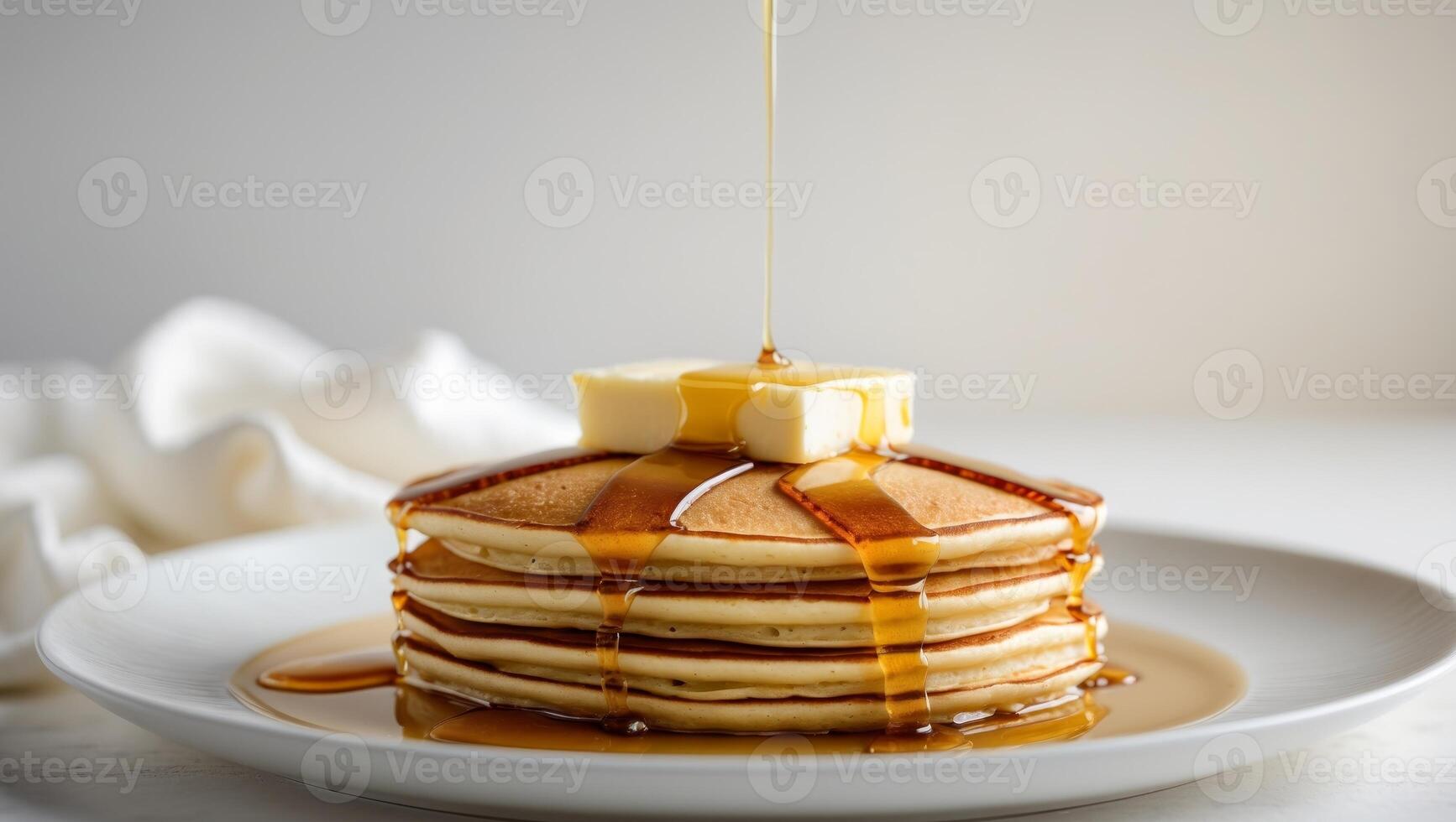 Stack of fluffy pancakes drizzled with syrup and melting butter on a white plate photo
